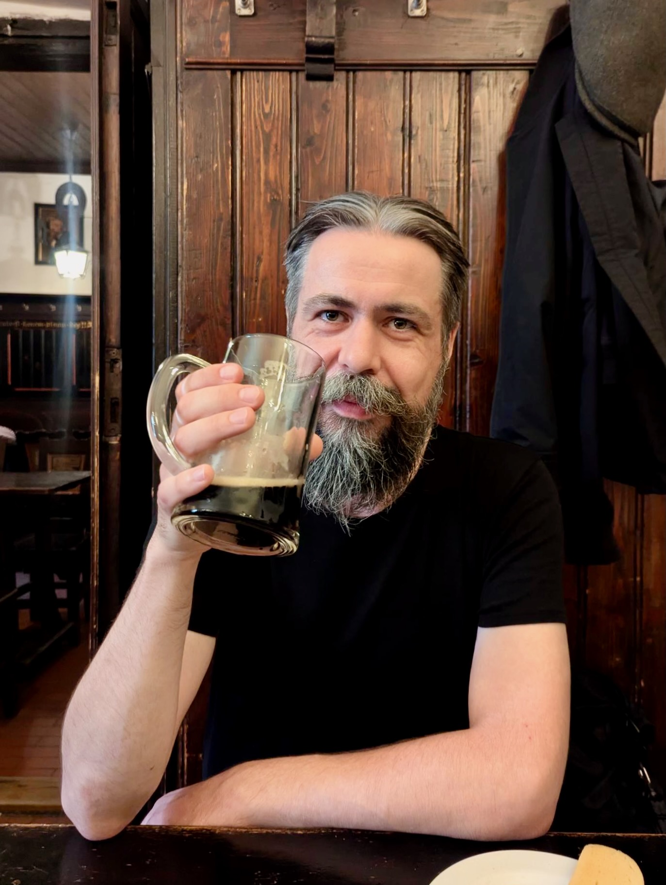 Ein bärtiger Mann hebt im Prager Brauhaus U Fleků einen fast leeren Krug mit dunklem Bier.